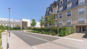 A residential street with modern apartment buildings, a clear sky, and a pedestrian pathway. - Flat in the Heart of Deauville With a Garden (Deauville)