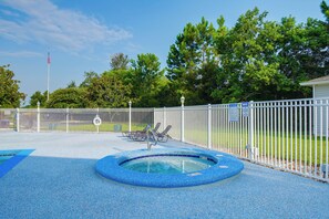 A swimming pool with a blue tiled edge, surrounded by a white fence, and a flagpole in the background. - Pool & Hot Tub Access! Family Condo, 5 Mi to Beach (Gulf Shores)