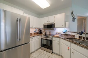A modern kitchen with stainless steel appliances, white cabinetry, and granite countertops. - Pool & Hot Tub Access! Family Condo, 5 Mi to Beach (Gulf Shores)