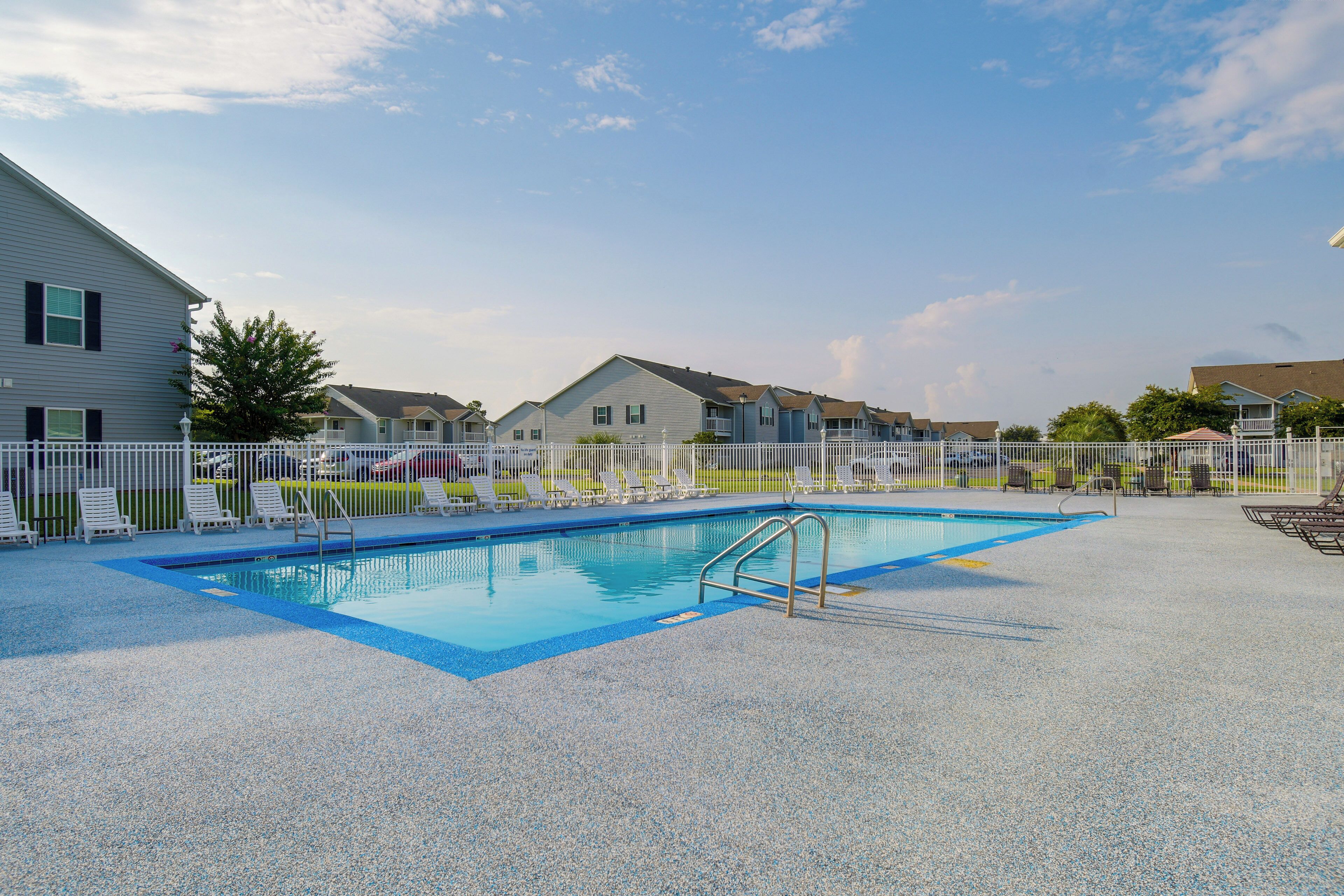 Una piscina con cerca blanca, rodeada de casas.