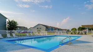 A swimming pool with a blue border, surrounded by a white fence, and adjacent to a row of houses. - Pool & Hot Tub Access! Family Condo, 5 Mi to Beach (Gulf Shores)