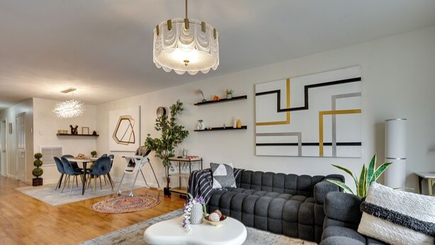 A modern living room with a sectional sofa, a dining area with a table and chairs, and a kitchen in the background. - Easy NYC Commute: Furnished Jersey City Home (Jersey City)