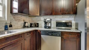 A kitchen with dark wood cabinets, a stainless steel dishwasher, a coffee maker, and a microwave. - Easy NYC Commute: Furnished Jersey City Home (Jersey City)