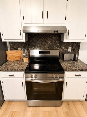 A kitchen with white cabinets, a stainless steel stove, and a microwave. - The Sumerville's Carriage House (Summerville)
