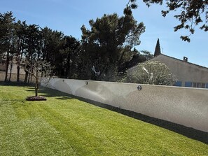 Uma área com grama, um muro baixo e árvores.