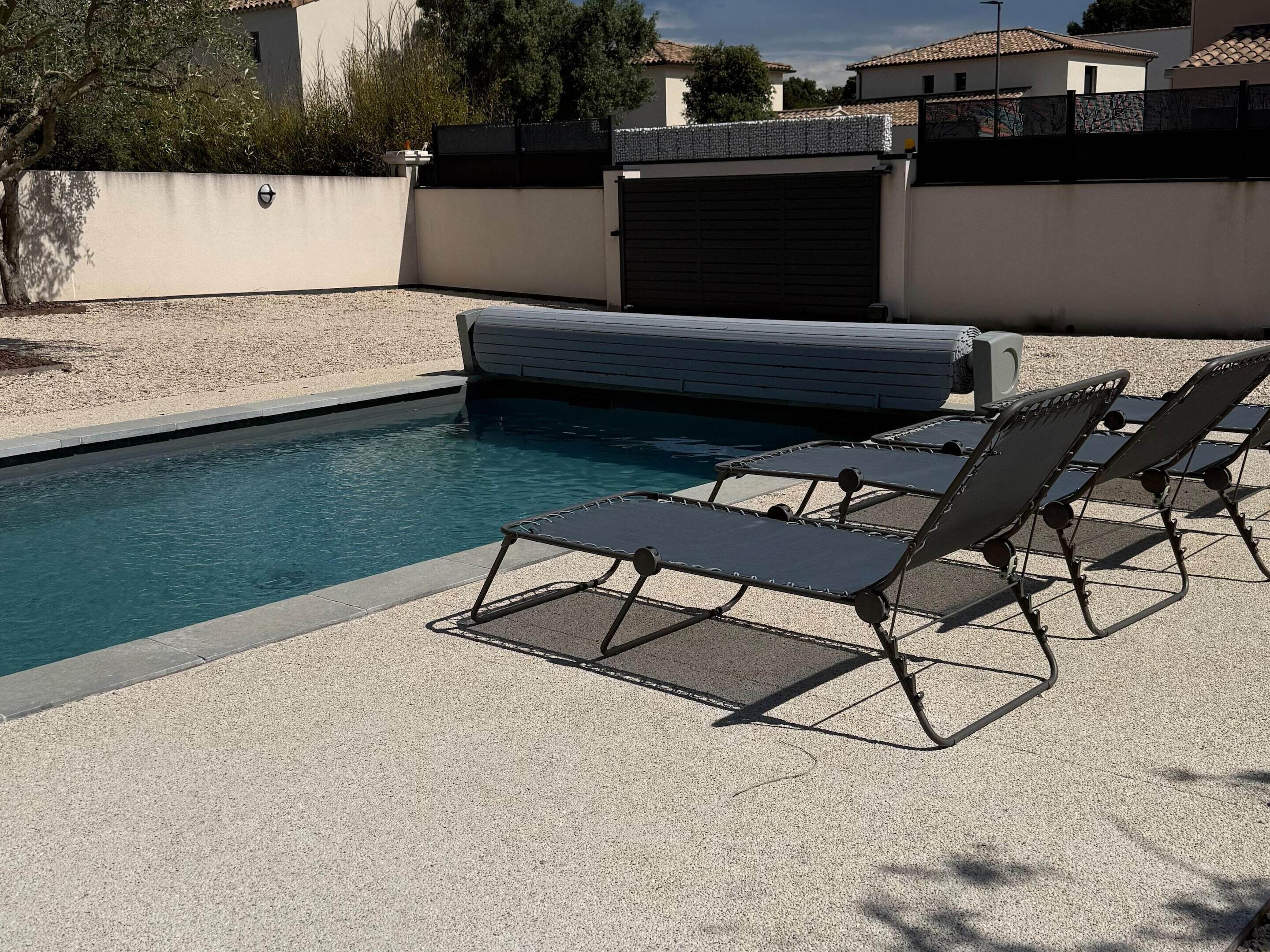 A swimming pool with lounge chairs and a covered area.