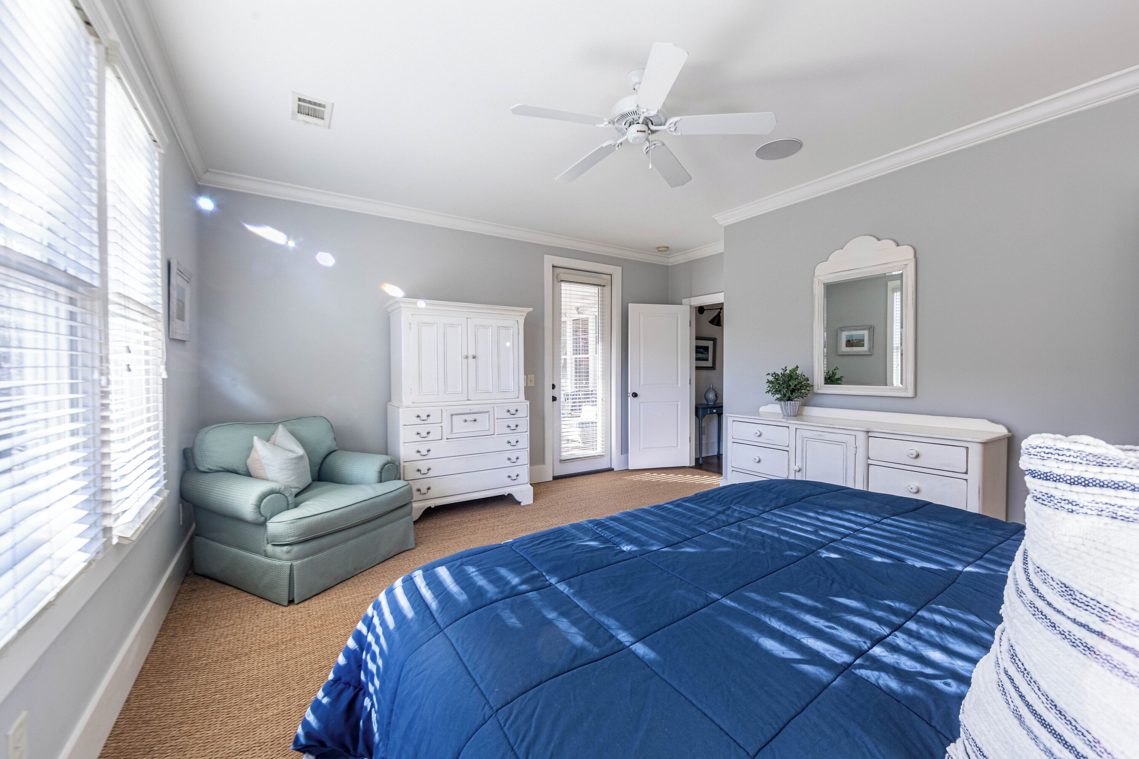 A bedroom with a bed, a dresser, a chair, and a ceiling fan.