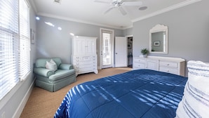 Un dormitorio con cama, cómoda, silla y ventilador de techo.