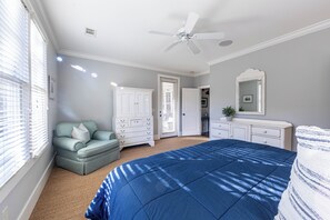 Ein Schlafzimmer mit Bett, Schminktisch, Stuhl und Deckenventilator.