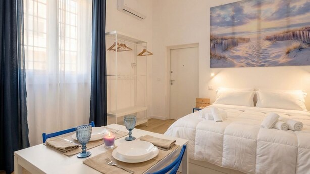 Una camera d'albergo con un letto, un tavolo da pranzo con una candela e un quadro raffigurante una spiaggia.