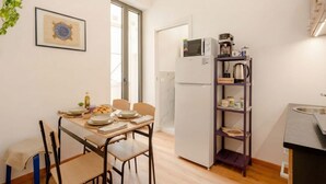 Una cucina compatta con frigorifero, microonde e macchina per il caffè.