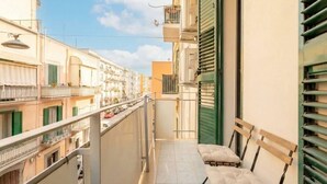 Un balcone stretto con una panchina e vista sugli edifici limitrofi.