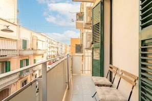 Ein schmaler Balkon mit einer Bank und Blick auf benachbarte Gebäude.