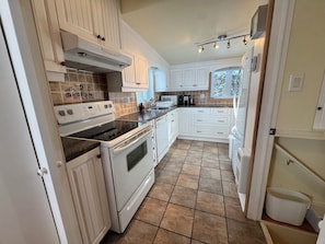 A kitchen with white cabinetry, a stove, oven, and a microwave. - Blue chalet right on the shore of Lake Brome (Lac-Brome)