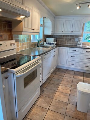 A kitchen with white cabinets, a stove, an oven, a microwave, and a sink. - Blue chalet right on the shore of Lake Brome (Lac-Brome)