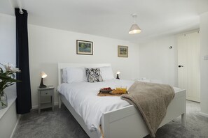 Ein Hotelzimmer mit Bett, Nachttischen, einem Frühstücksbrett und einer Tür.