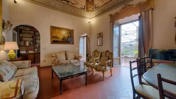 A spacious living room with a sofa, armchairs, a coffee table, and a television. There is a bookshelf and a painting on the wall. - Large 4-bedroom apartment (Firenze)