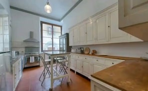 Eine Küche mit weißen Schränken, einer Holz Arbeitsplatte und einem Essbereich mit Stühlen.