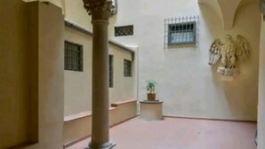 A corridor with a column, a potted plant, and a wall-mounted sculpture. - Large 4-bedroom apartment (Firenze)
