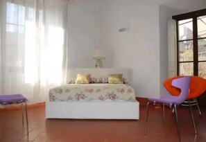 Een slaapkamer met een bed, een stoel en een raam.