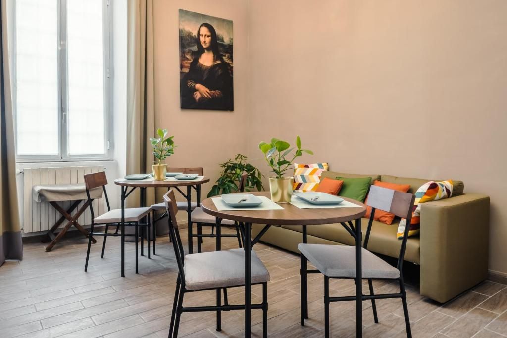A dining area with a table, chairs, and a painting on the wall.
