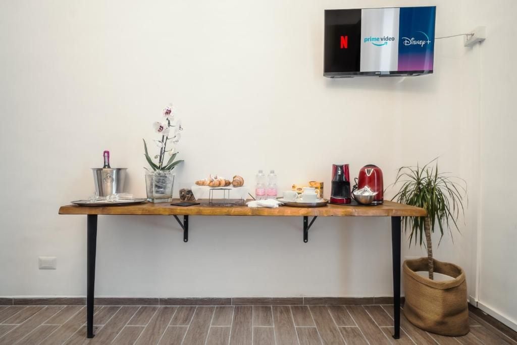 Un espace d’accueil avec une longue table où sont exposées des pâtisseries, une machine à café et une plante en pot.