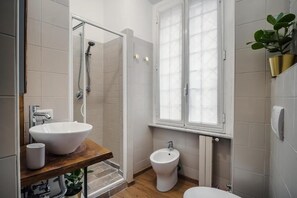 Ein Badezimmer mit einem großen weißen Waschbecken, einem Bidet und einer Dusche.