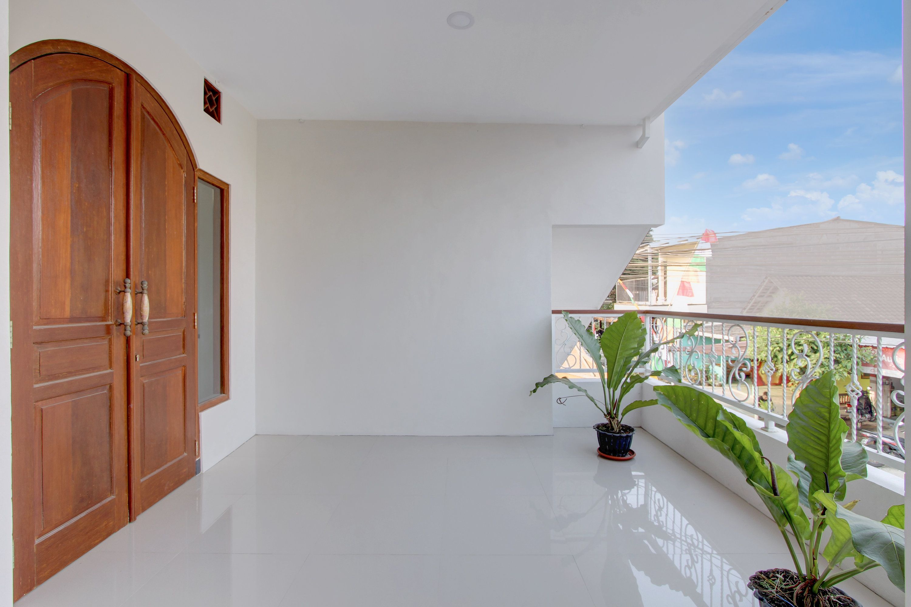 Un balcone con una porta in legno, una pianta in vaso e una vista libera sulla strada.