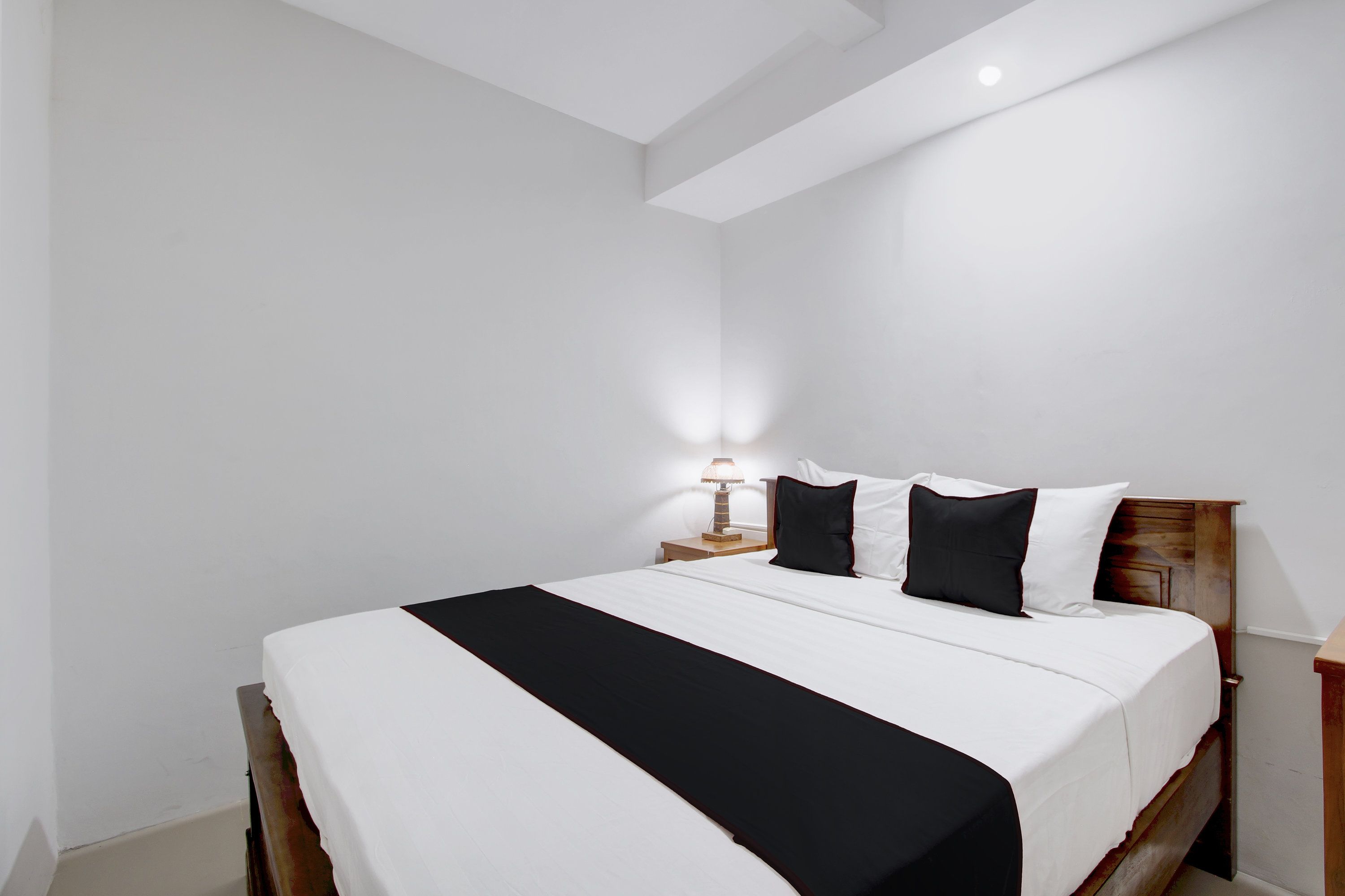 A hotel room with a large bed, a nightstand with a lamp, and a wooden headboard.