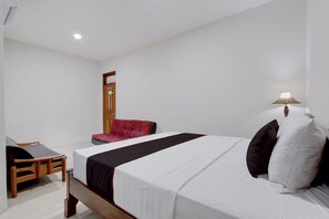 Ein Hotelzimmer mit Bett, Sessel, Schreibtisch und Lampe.