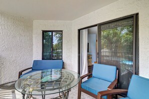 A glass-top table with chairs, a view of a swimming pool, and a door leading to another room. - Ocean Oriented Oasis!  Indoor Heated Pool!  Pickleball! Hot Tub! (Hilton Head)