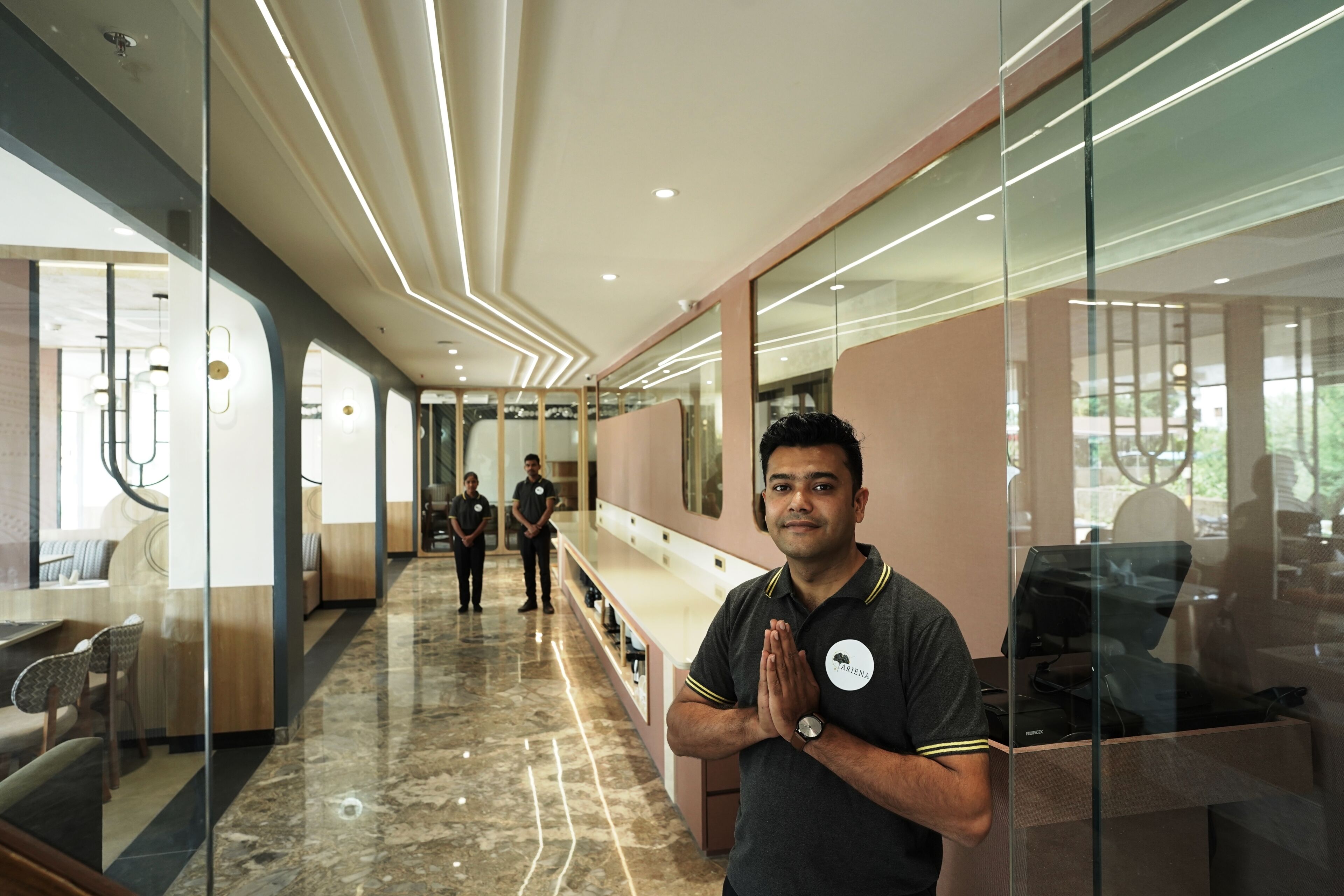 Um interior moderno com piso de mármore, divisórias de vidro e uma área de estar com cadeiras.