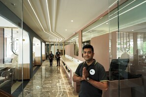 A modern interior with a marble floor, glass partitions, and a seating area with chairs. - Hotel Cloud by ARIENA (Raipur)