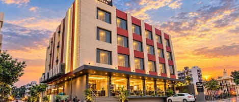 A hotel with a modern facade, multiple floors, and a prominent entrance with outdoor seating.