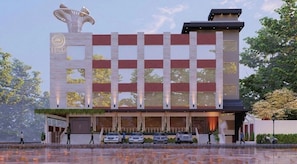 A modern hotel with a symmetrical facade, a central entrance, and a parking area with cars.
