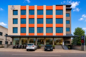Un hotel de fachada moderna, varios pisos y cielo despejado.