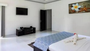 Una habitación de hotel moderna con una cama, un televisor de pantalla plana, un ventilador de techo y un cuadro en la pared.