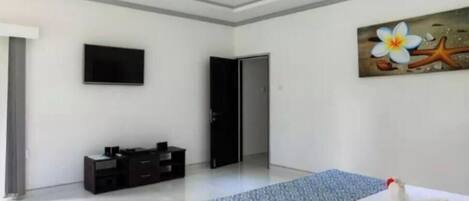 A modern hotel room with a bed, a flat-screen TV, a ceiling fan, and a painting on the wall.
