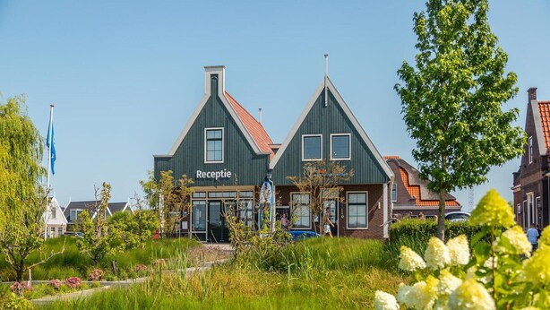 En bygning med et skilt, der viser 'Receptie', foran et frodigt grønt landskab.