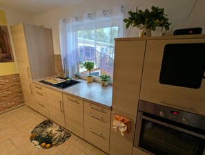 A kitchen with a built-in oven, a sink, and a window with a view of the outside. - Cozy Vacation Home Near the Baltic Sea in Kröpelin (Kröpelin)