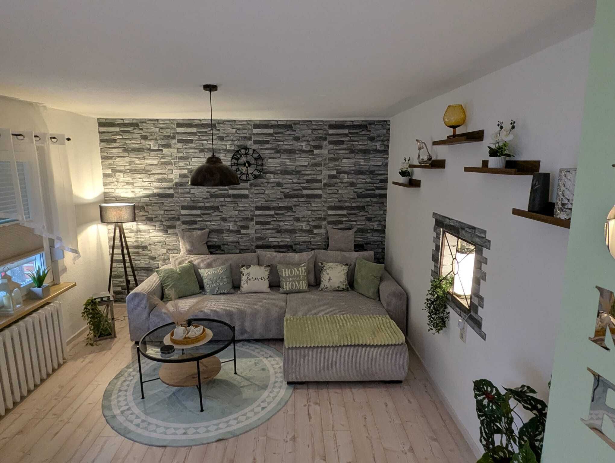 A living room with a stone wall, a sofa, a coffee table, and a lamp.