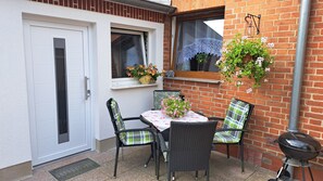 An outdoor patio with a table and chairs, a barbecue grill, and potted plants. - Cozy Vacation Home Near the Baltic Sea in Kröpelin (Kröpelin)