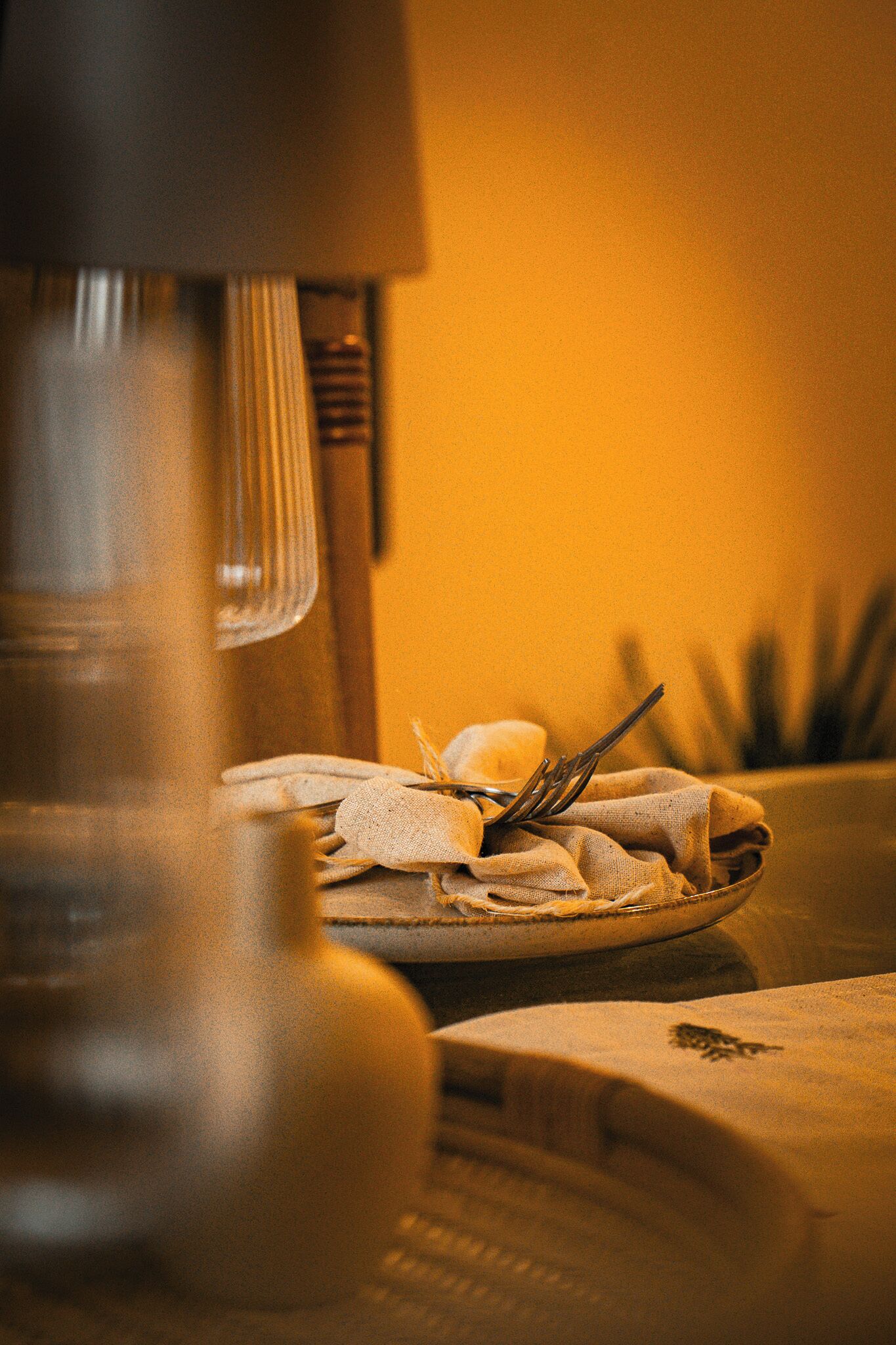 Un coin cuisine avec un batteur, une assiette recouverte d’un torchon et un ustensile, ainsi qu’une plante en arrière-plan.