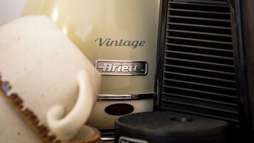 Una cafetera de estilo vintage y un teléfono con dial rotativo sobre una superficie de madera.