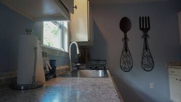 A kitchen with a stainless steel sink, a refrigerator, and a window providing natural light.