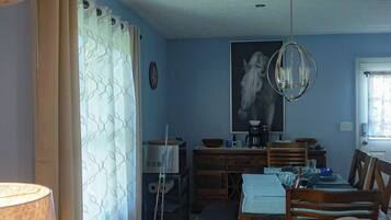 A dining area with a table set for four, a chandelier, and a painting on the wall.