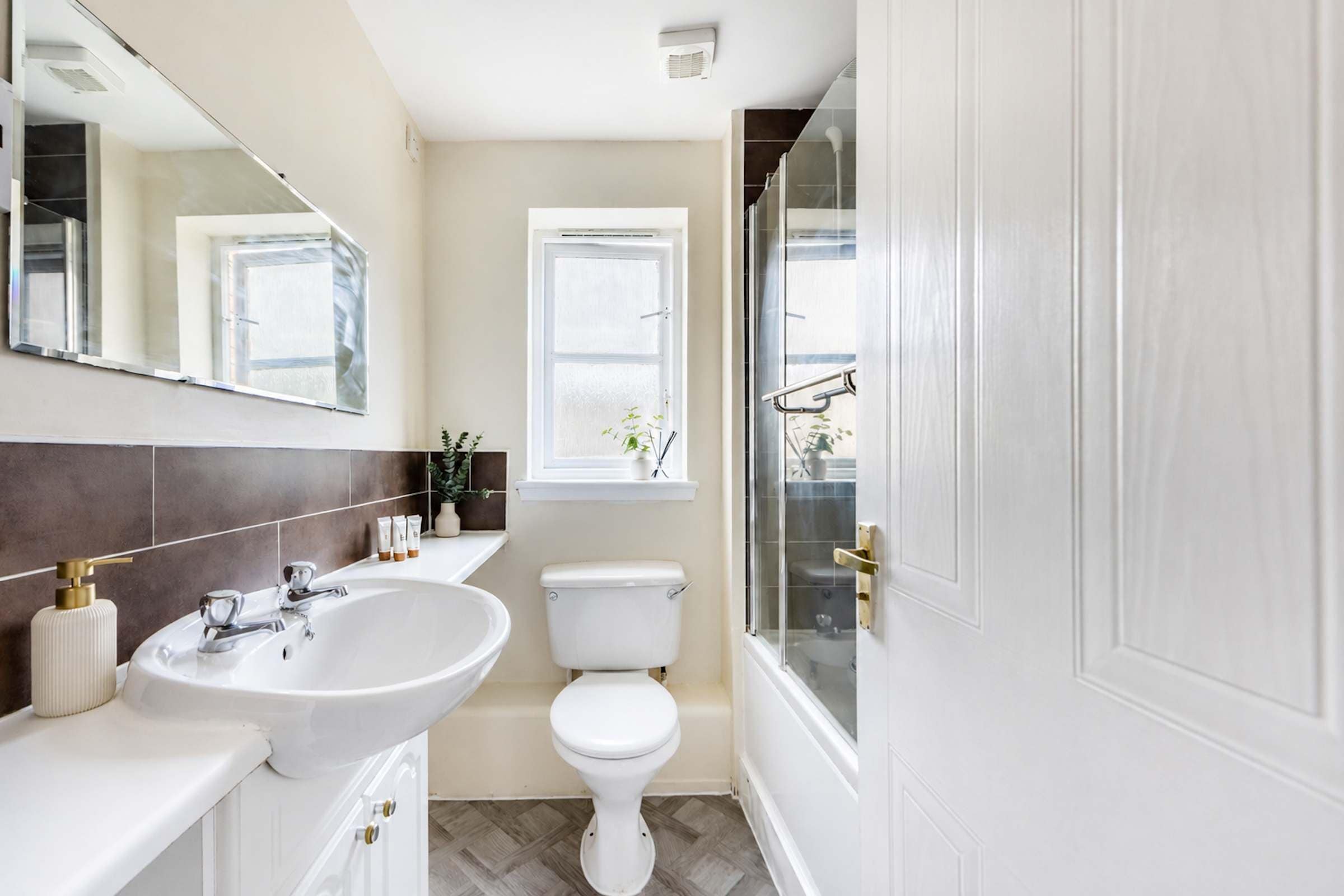 A bathroom with a white sink, toilet, and shower area.