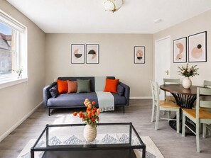 A living room with a sofa, coffee table, and dining area. - Charming 2BR Flat Near Holyrood Park & Old Town (Edinburgh)