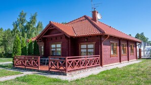 Ett trähus med ett rött tak, en balkong och en satellitparabol.