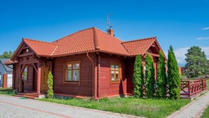 Ett trähus med ett rött tegeltak, en skorsten och en liten veranda.